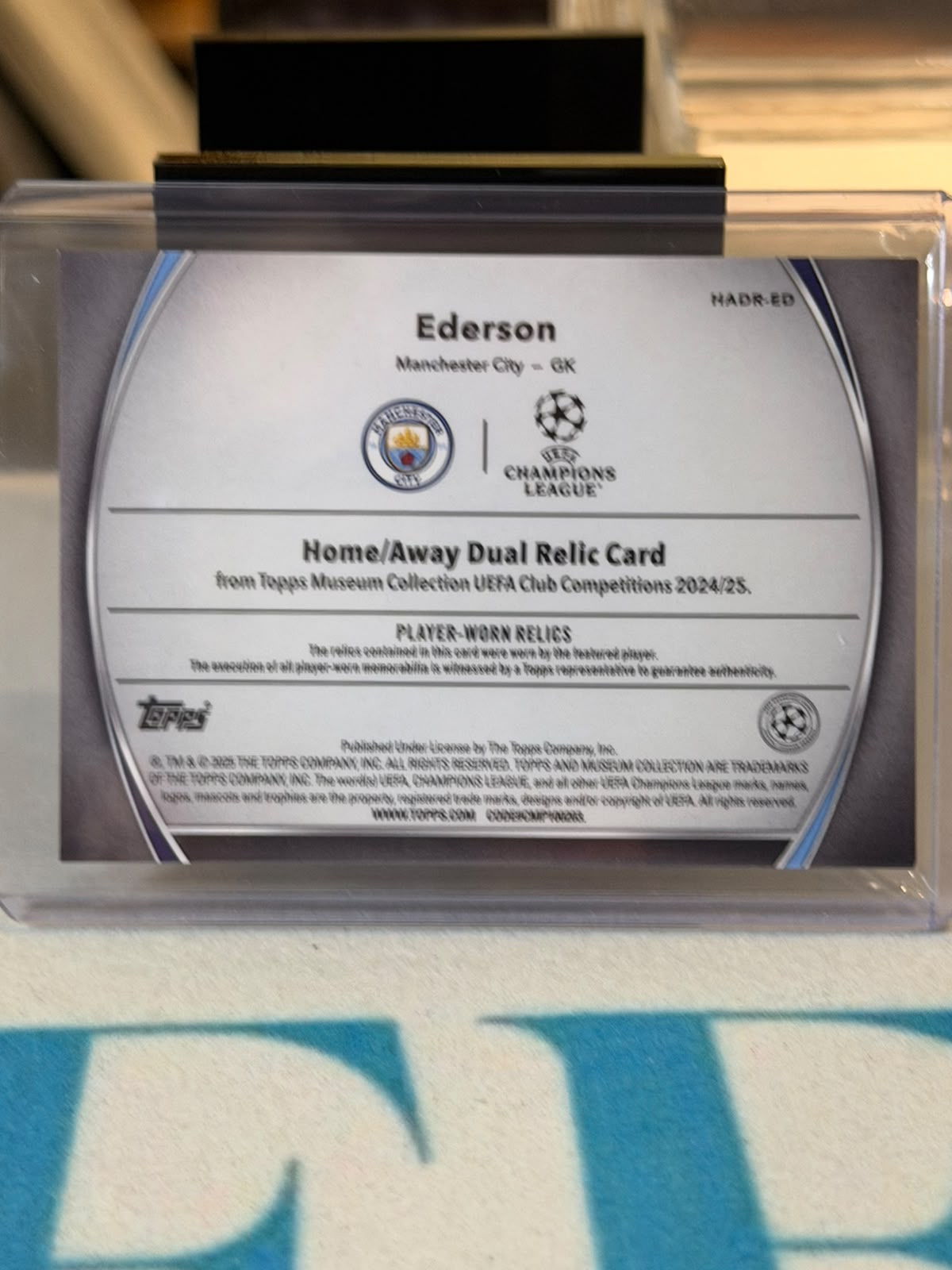 Ederson 08/99 – Home/Away Dual Relic – 2024-25 Topps Museum Collection UEFA Club Compet… – Manchester City trading card, back