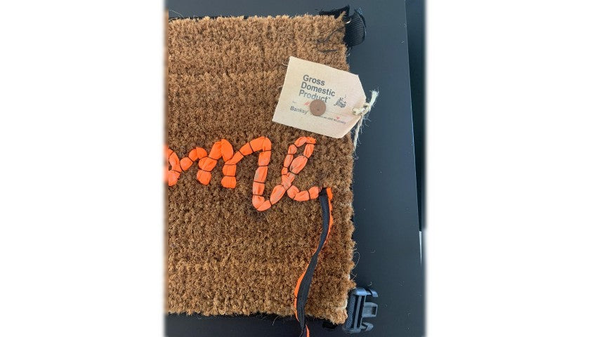 Banksy's "Welcome Mat" shown in its original packaging